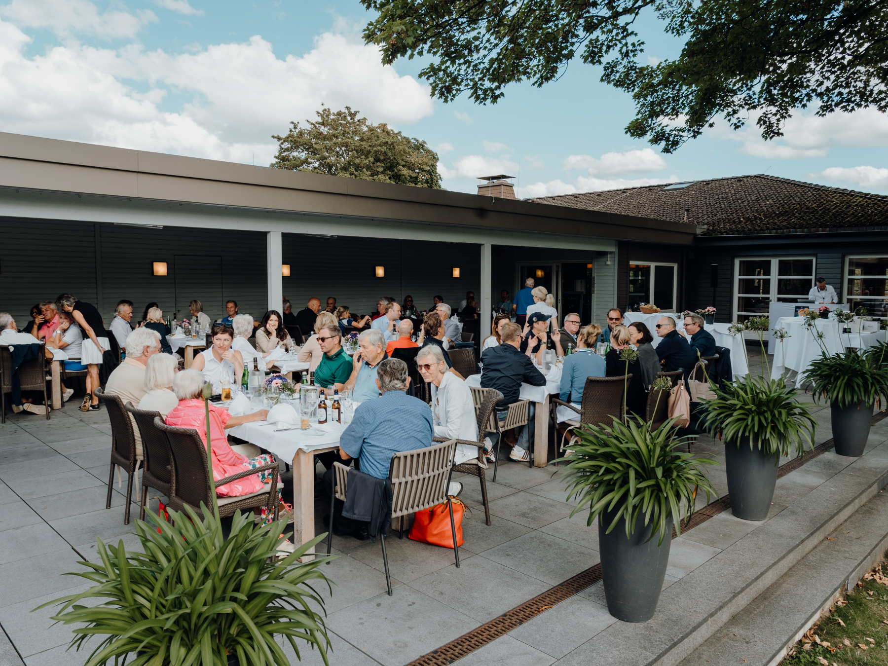 Gäste bei einer Veranstaltung auf der überdachten Terrasse des Aachener Golf-Club Clubhauses